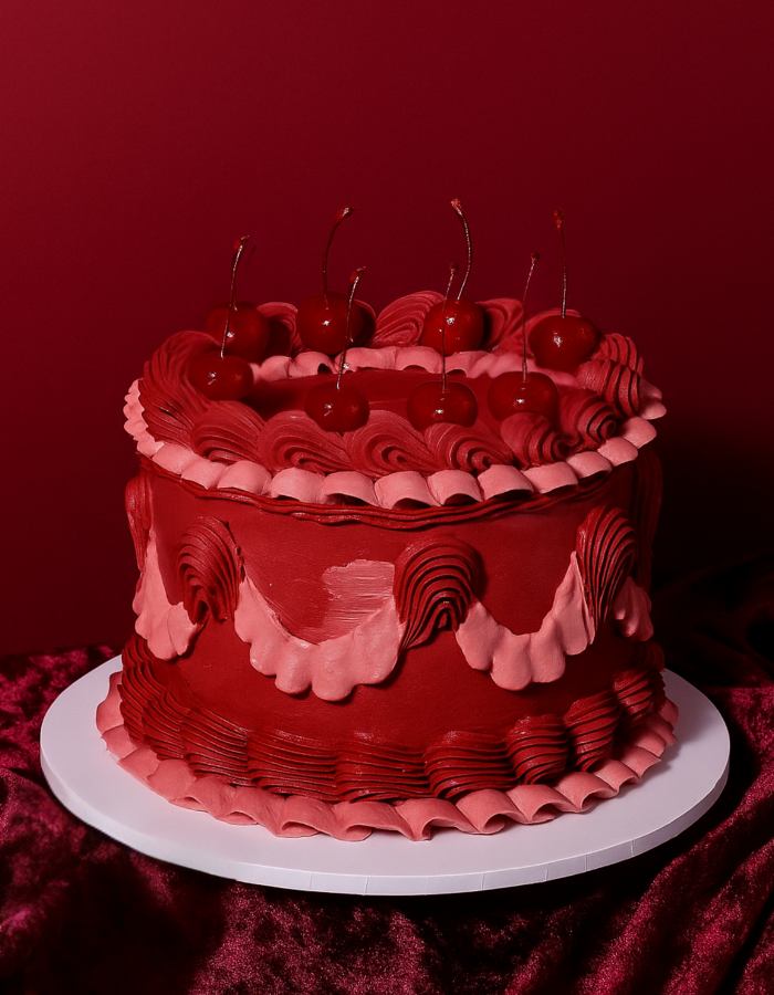 Knallroter dekorierter Bento Cake mit Kirschen auf rotem Hintergrund und Samttuch