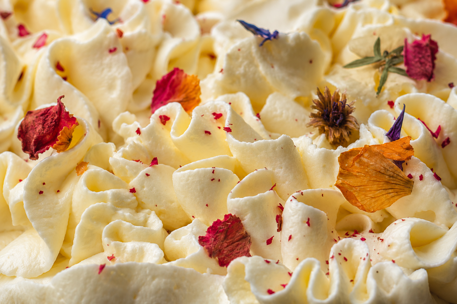 Cream Cheese Frosting auf einem Hummingbird Cake mit essbaren getrockneten Blüten als Dekoration