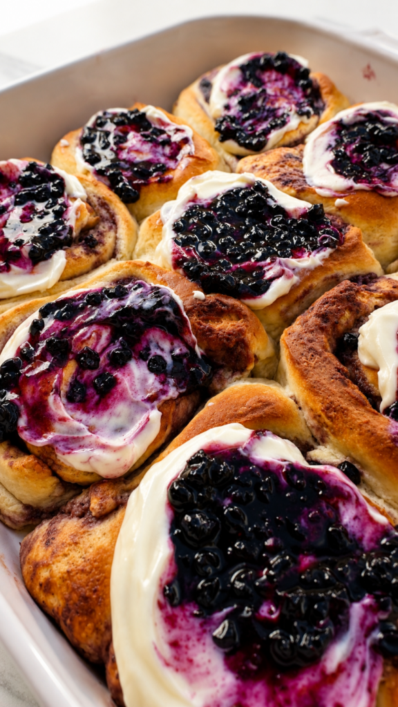 Warme Wildheidelbeer Cinnamon Rolls mit cremigem Frischkäse-Frosting.