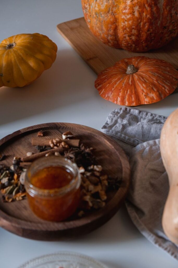A cozy still life featuring pumpkins and spiced jam perfect for fall.